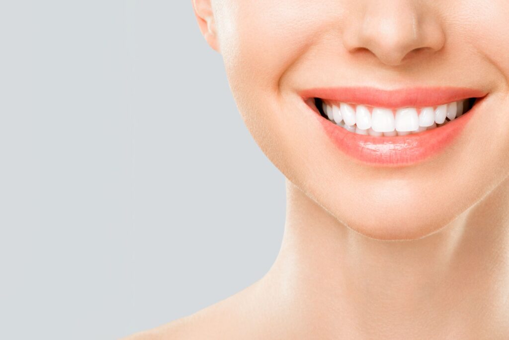 Nose-to-neck view of woman smiling with a gray background