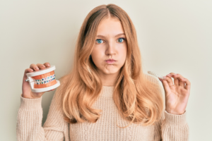 a patient holding a clear aligner and braces model